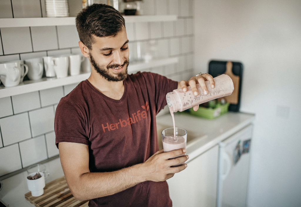 Man pouring a shake in his kitchen