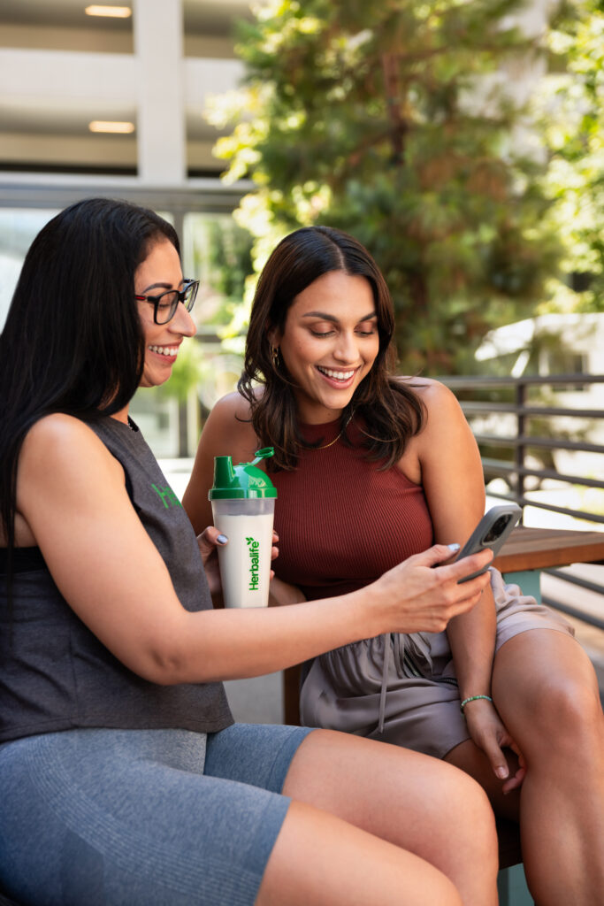 Two women smiling while looking at a cell phone